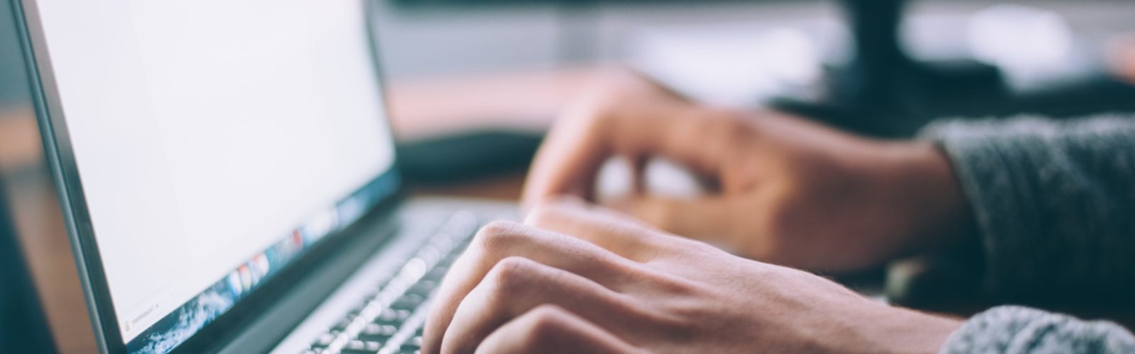 close-up of hands typing on laptop computer keyboard